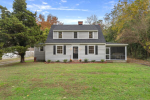 Front exterior of updated home for sale in White Stone, VA with screened porch, dormer windows, and landscaped front yard.