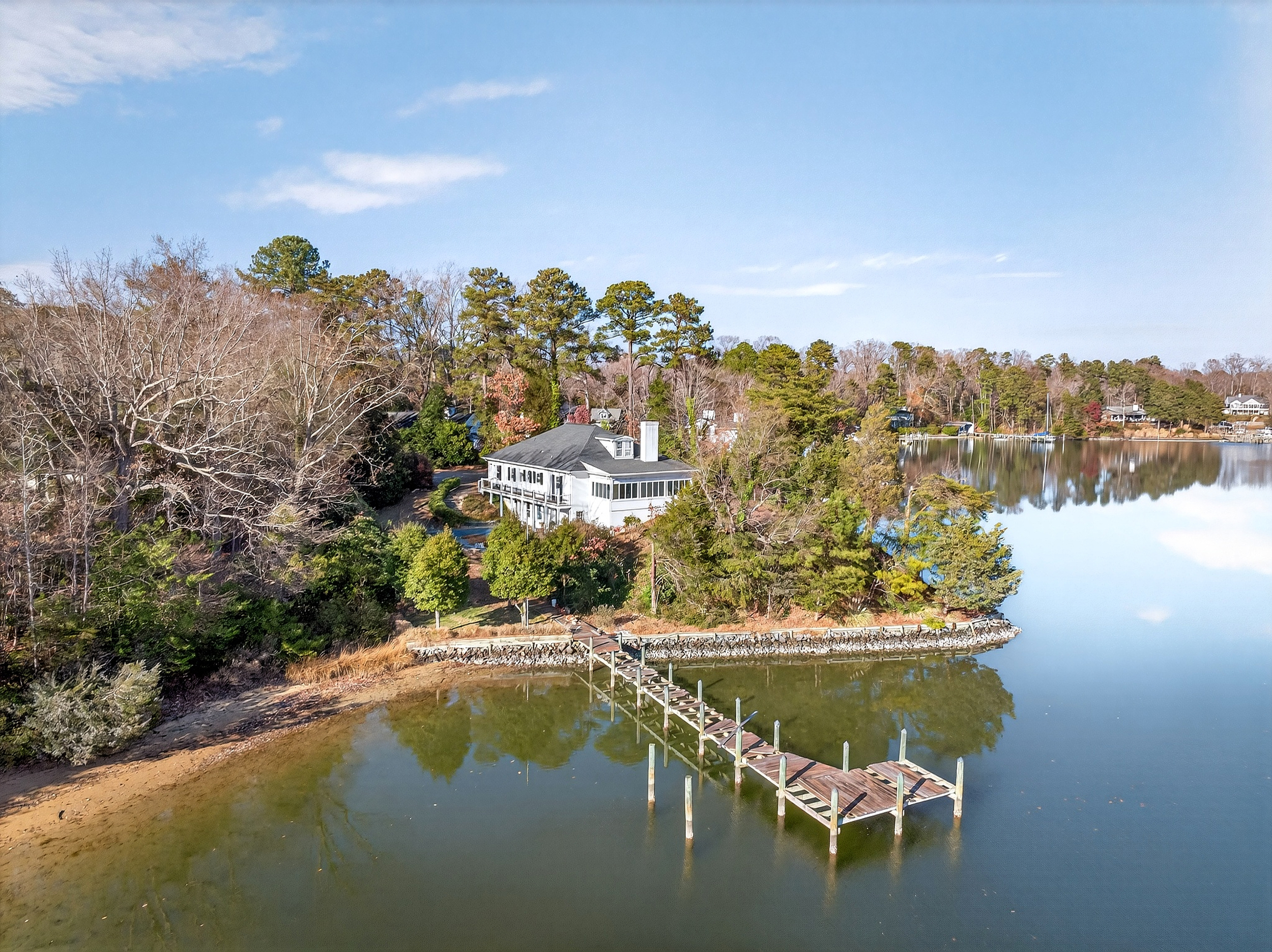 Aerial view of brick waterfront home on Carter’s Creek in Weems, VA, showing 250-degree shoreline, private dock, and surrounding water.